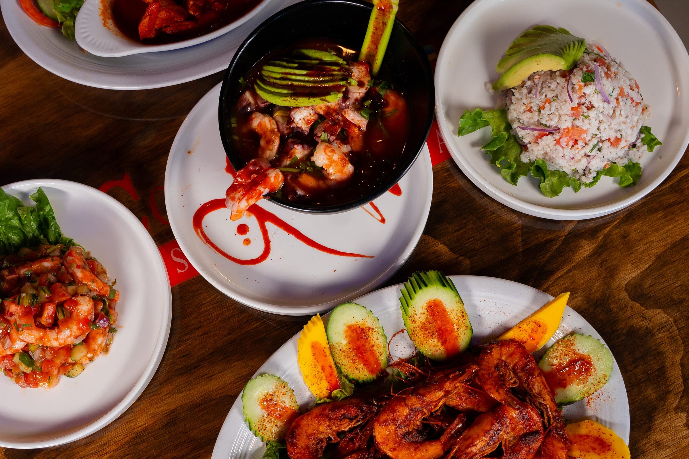 Mesa con ceviches, aguachile negro y camarones a la parrilla de Mariscos Costa Alegre